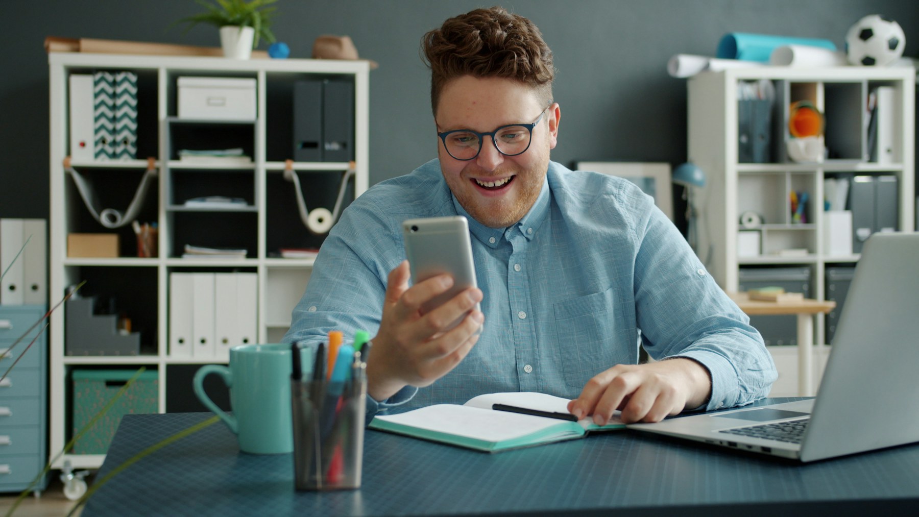 A broker on a phone call, taking notes at a desk.