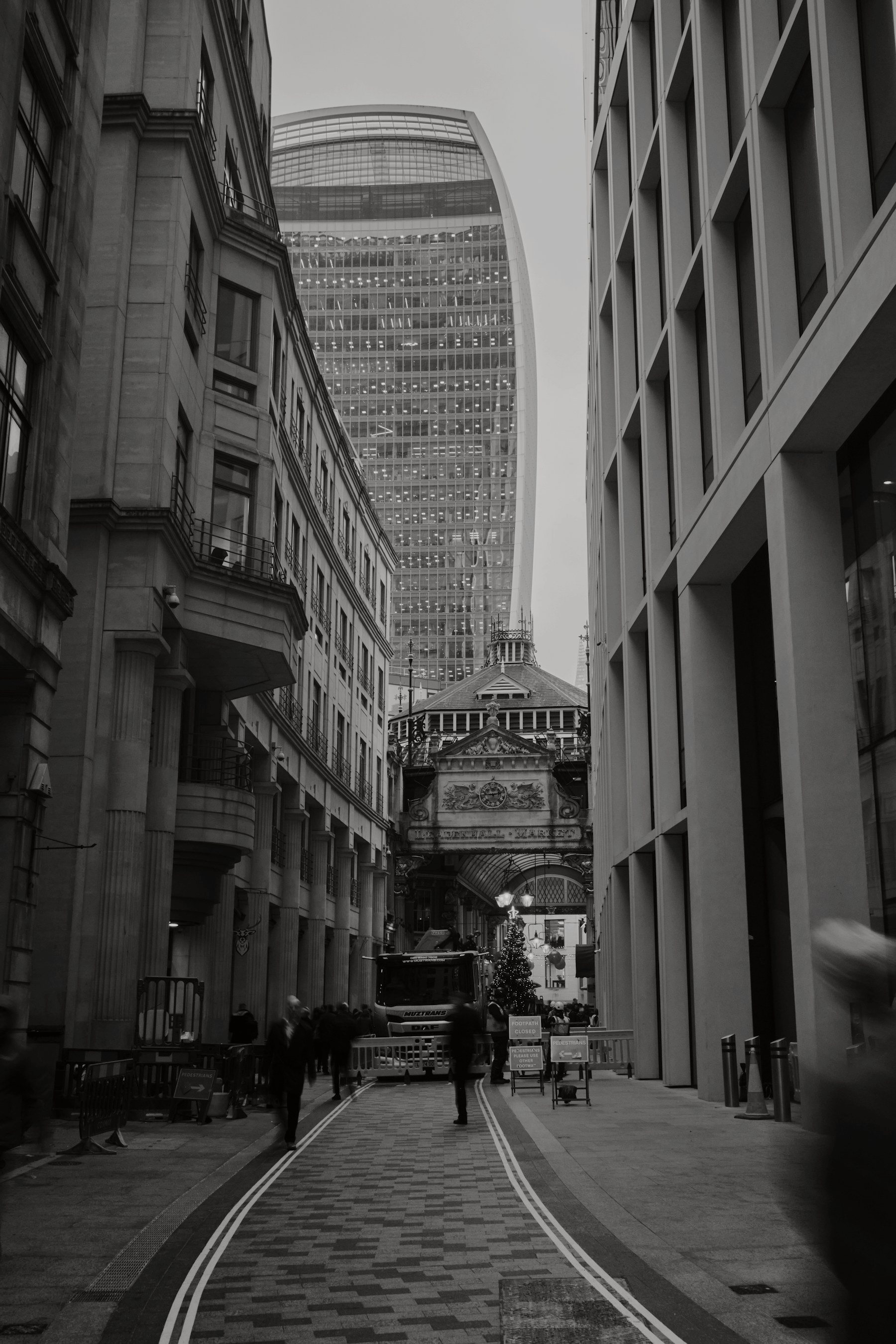 A City of London street looking towards the Victorian entrance of Leadenhall Market, with a modern tower behind it.